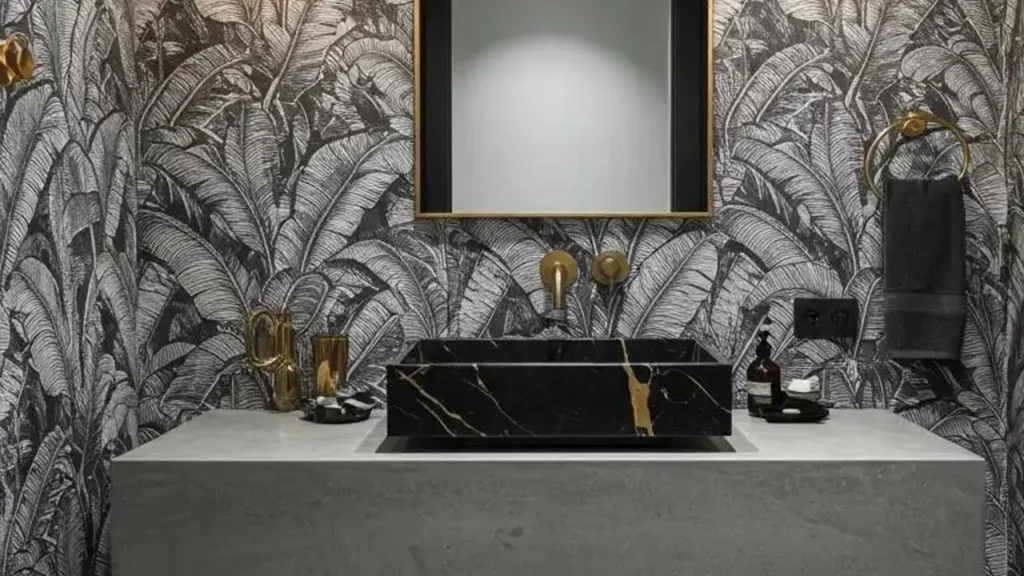 Modern tropical bathroom with palm print wallpaper, gold accents, and a black veined marble sink.