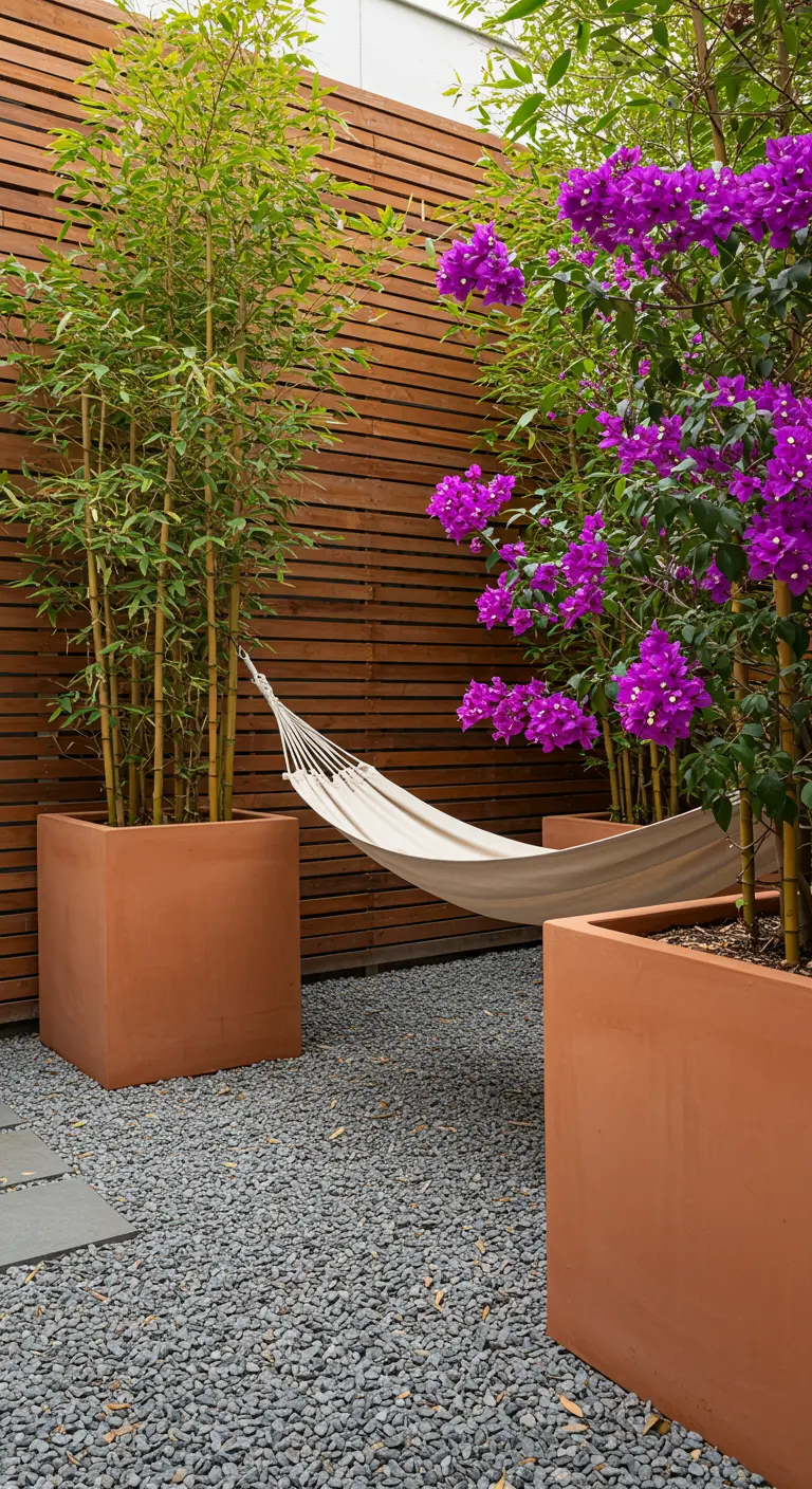 A modern patio with a hammock hanging between two large planters holding bamboo and bougainvillea.