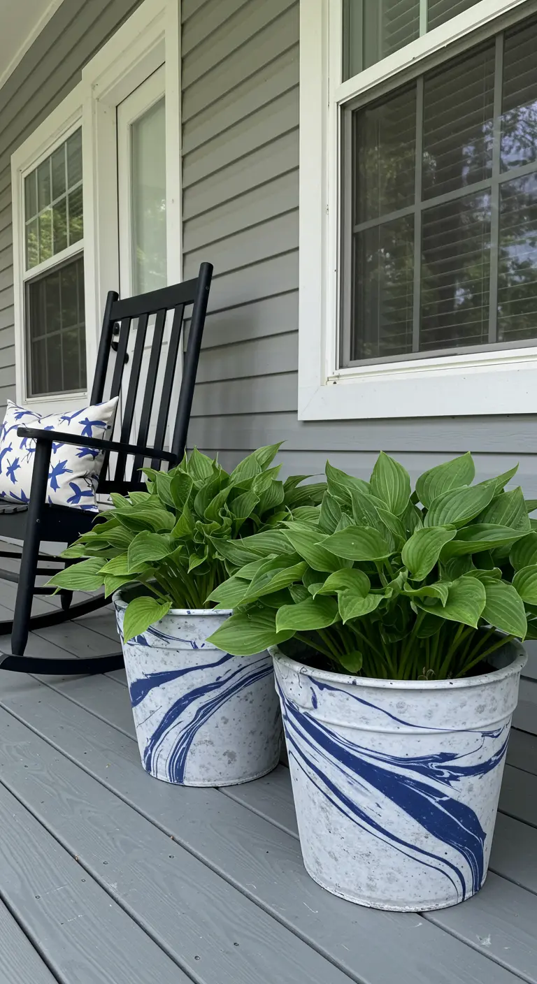 Two galvanized metal planters with a blue and white marble finish, filled with hosta plants.