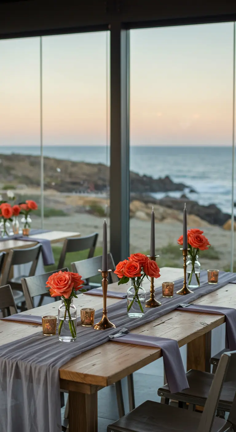 Minimalist table setting with coral roses in bud vases and gray candles by the sea.
