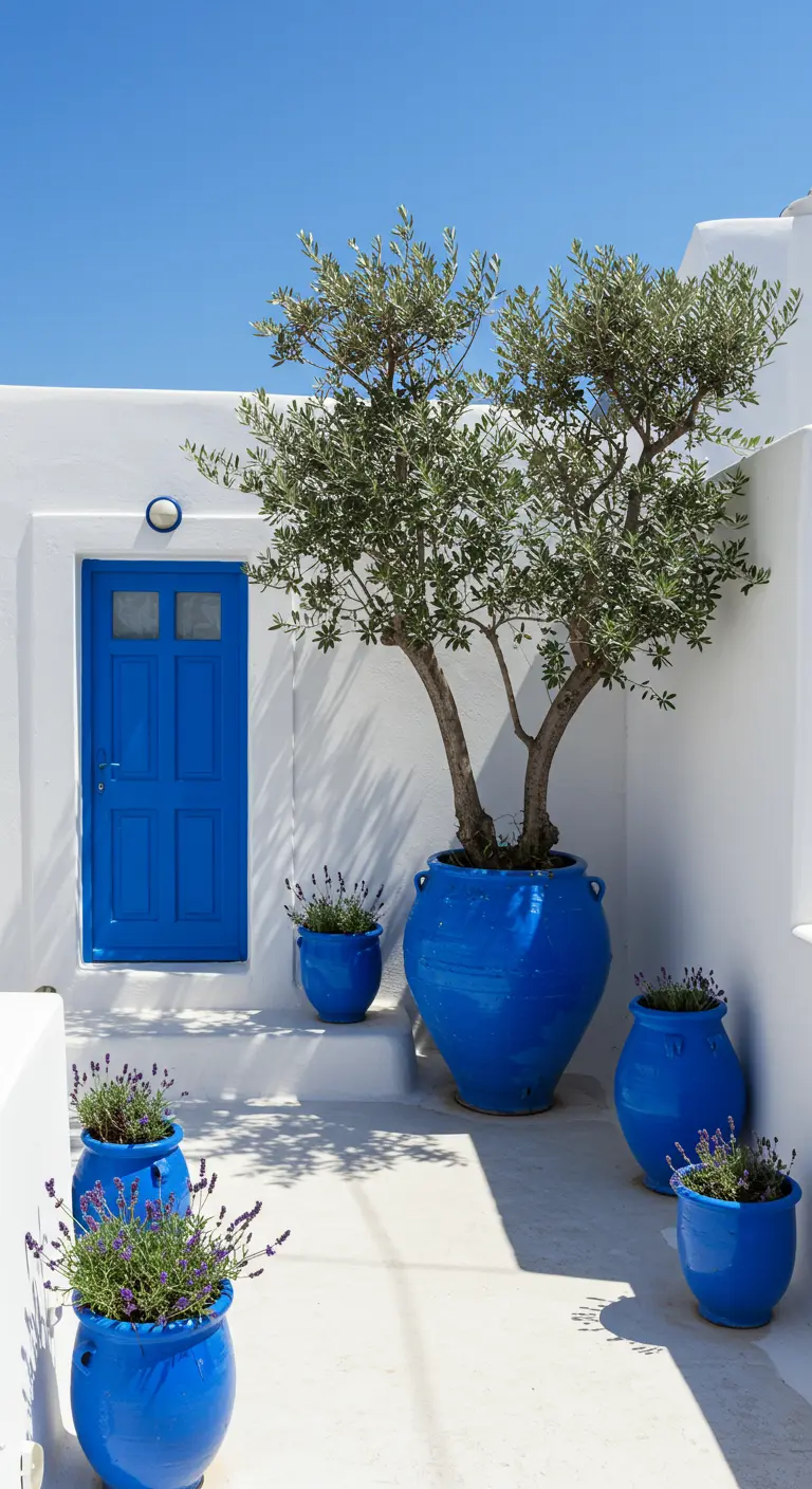 Whitewashed Greek courtyard with a blue door and matching cobalt blue pots with lavender.