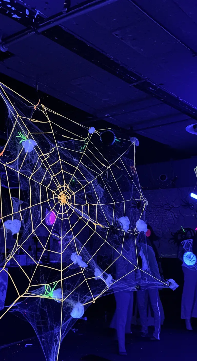 A giant glow-in-the-dark spider web decoration with spiders and cotton ball nests.